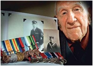 William Evan Allan on his 100th bithday poses with the service medals he won in both world wars and with pictures of him as a young sailor and petty officer.